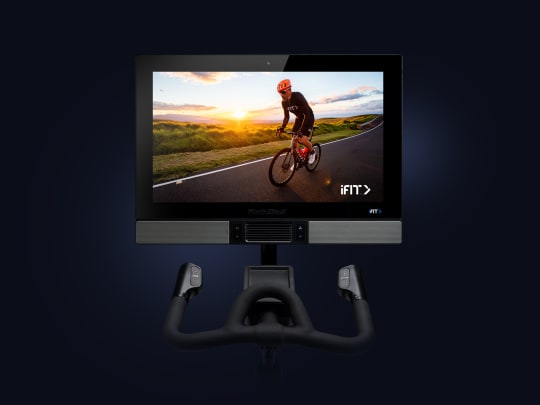Top half of bike shown including screen and handlebars. iFIT trainer is riding a bike on the screen.
