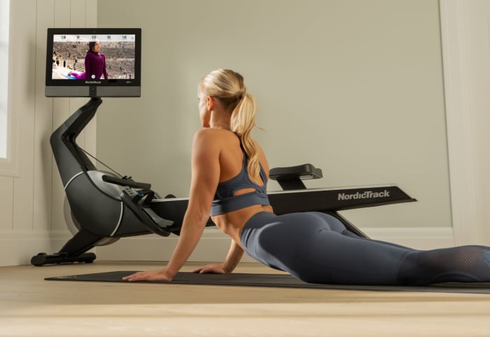 woman doing yoga next to the rw900 rower