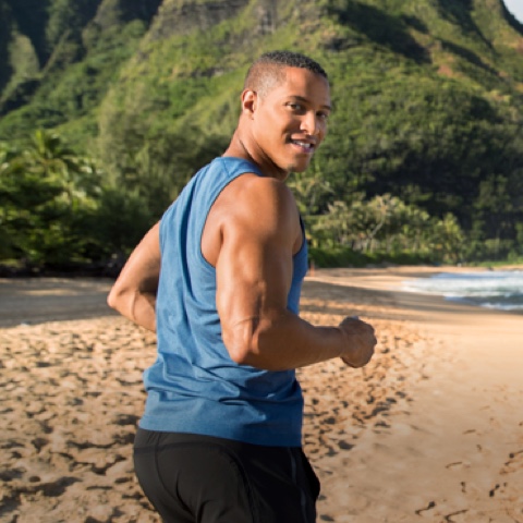 Coach running on beach and looking back at camera as if to encourage you to give it your all
