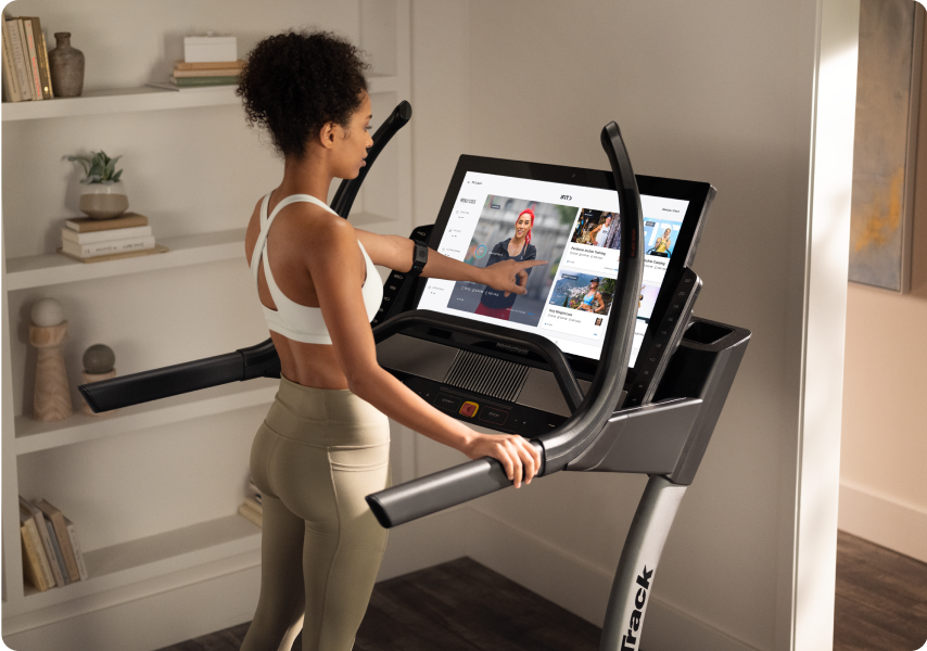 woman on her nordictrack incline trainer interacting with the HD touchscreen display