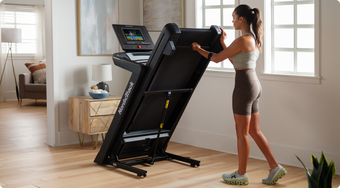 Woman folding her NordicTrack treadmill for storage.